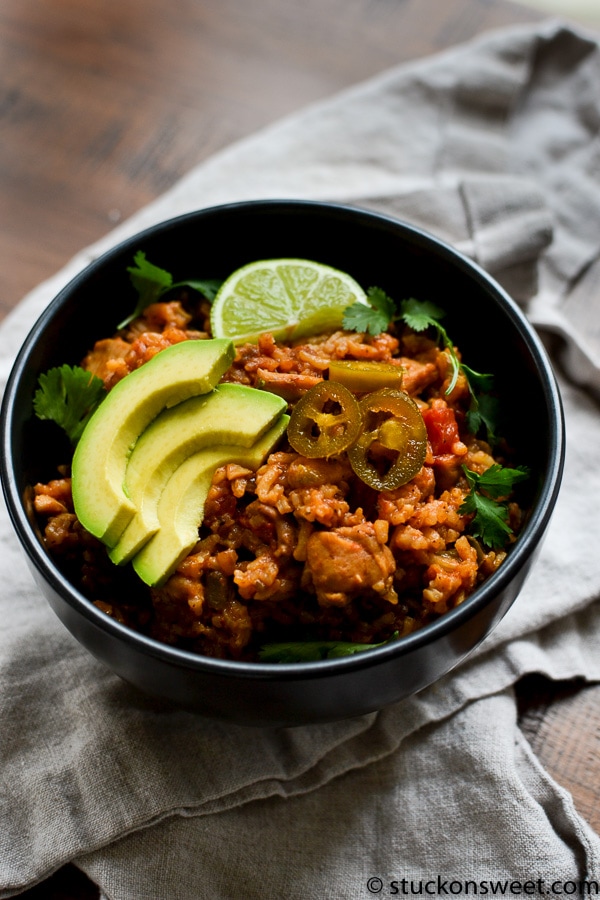 Mexican Rice in black bowl with avocado, jalapeños, and cilantro.