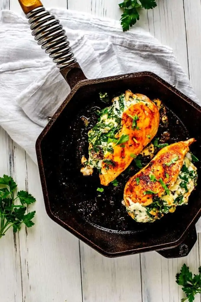 Image of two pieces of Keto Stuffed Chicken in a skillet against a white backdrop.