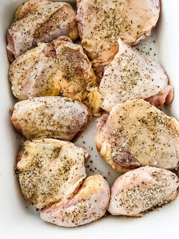 Seasoned chicken thighs placed in a baking dish.