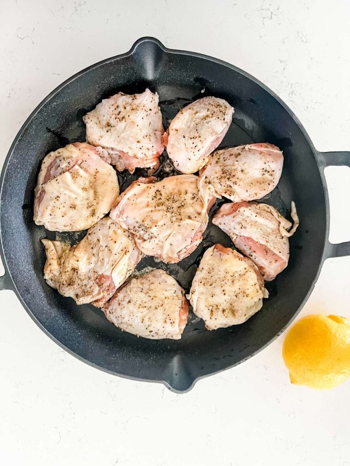 Chicken thighs in a cast iron skillet, ready to be baked.