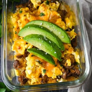 Overhead view of an egg and cheese breakfast bowl, adorned with sliced avocado.