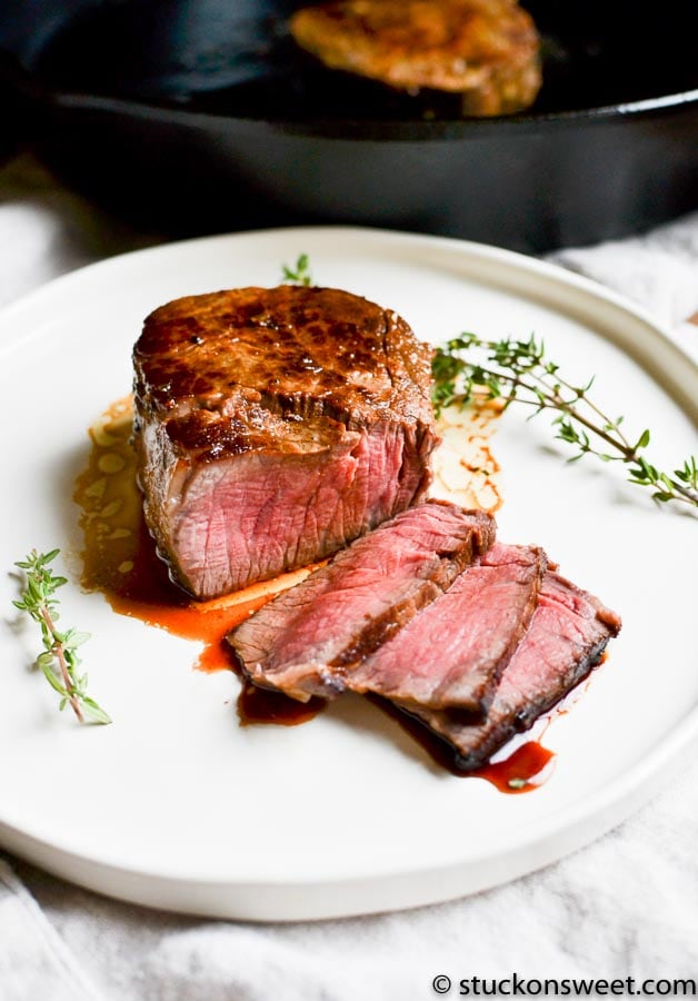 juicy filet mignon on a white plate with herbs 